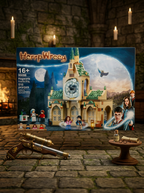 Harry Potter Hogwarts Castle building set box displayed on a stone floor with candles and a brass telescope prop in the foreground.
